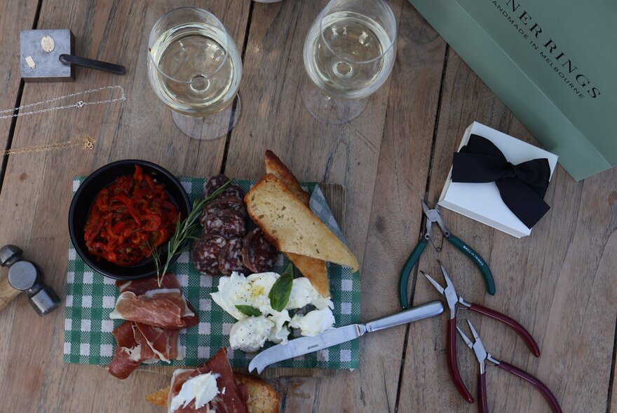 Grazing board with cheese, meats and toast next to glasses of wine.