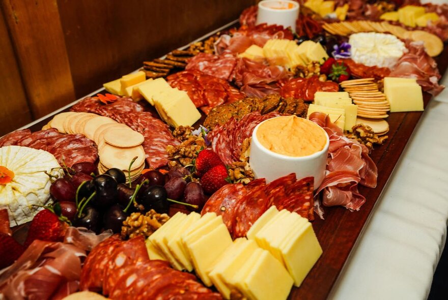 A grazing table with cured meats, cheese and dip.