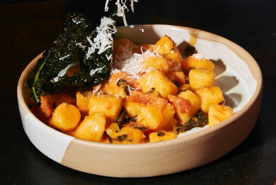 Closeup of a bowl of gnocchi with grated parmesan.