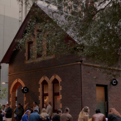 People seated outside the brick Caretaker's Cottage bar on a winter's day as light is fading.