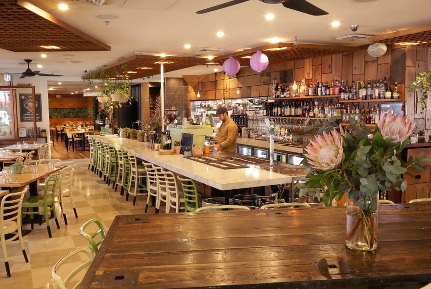 The interior of a restaurant and bar with lots of timber and a bartender. 