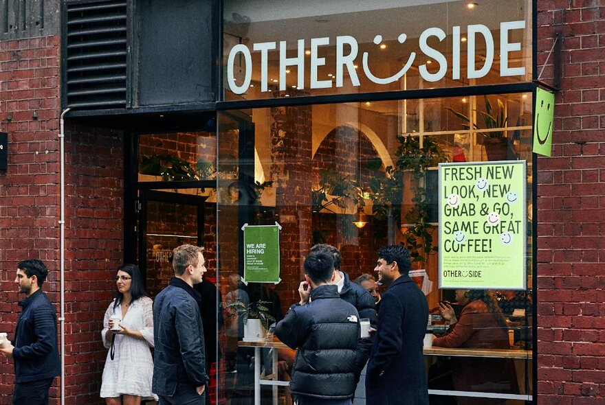 People standing outside a cafe waiting for takeaway coffee.