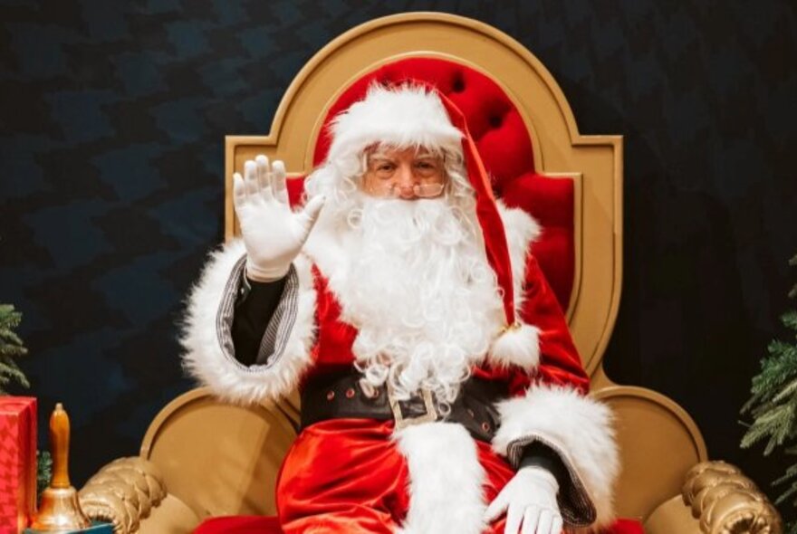 Santa seated on a throne, one hand raised.