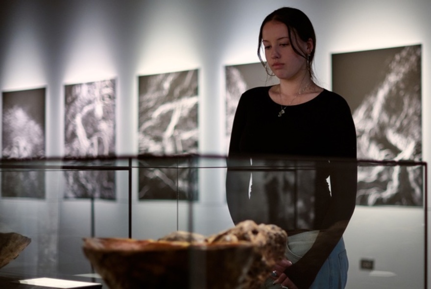 A person looking at a bowl in a display case.