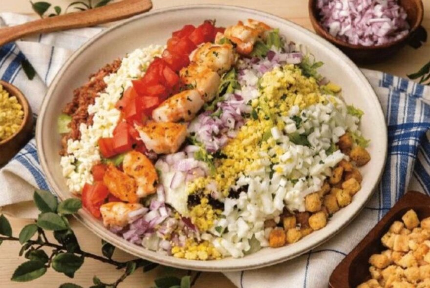 Prawn and vegetables arranged in colourful rows in a bowl.