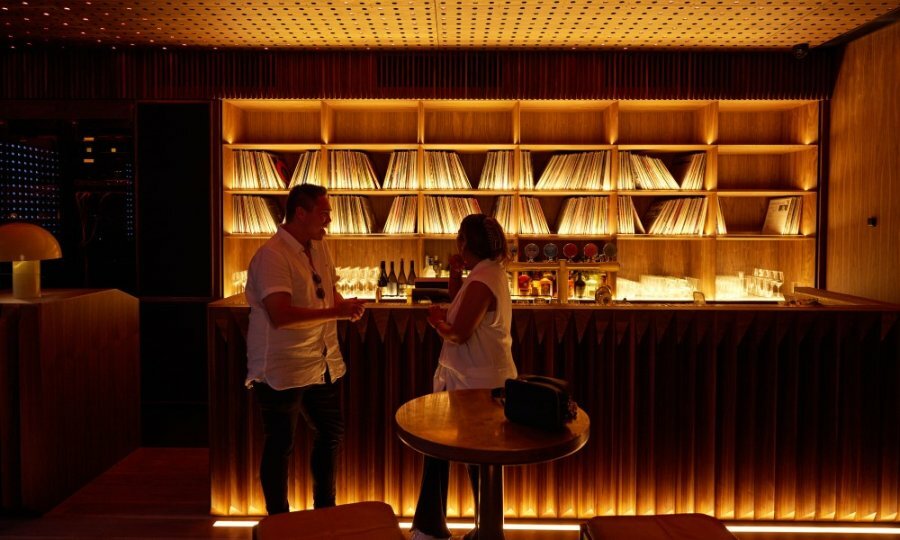 Two people at a bar with vinyl records lining the shelves.