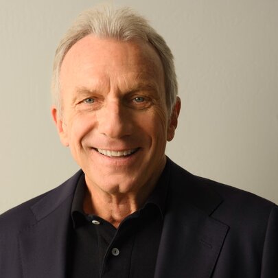 NFL legend Joe Montana, wearing dark suit and smiling.