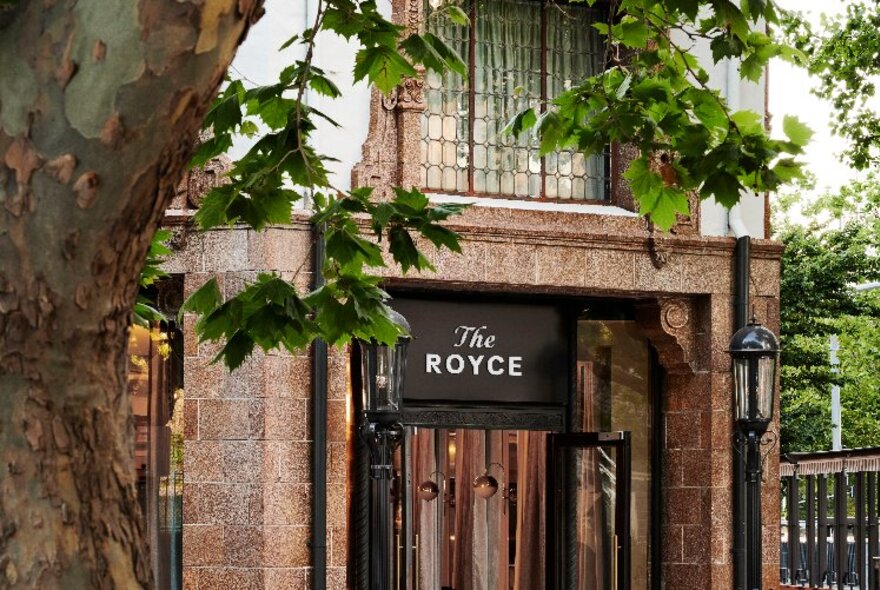 The exterior of The Royce with a marble entrance and an old fashioned lamp post.