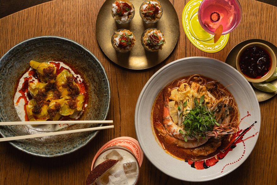 Dishes of Asian food with chopsticks and drinks.