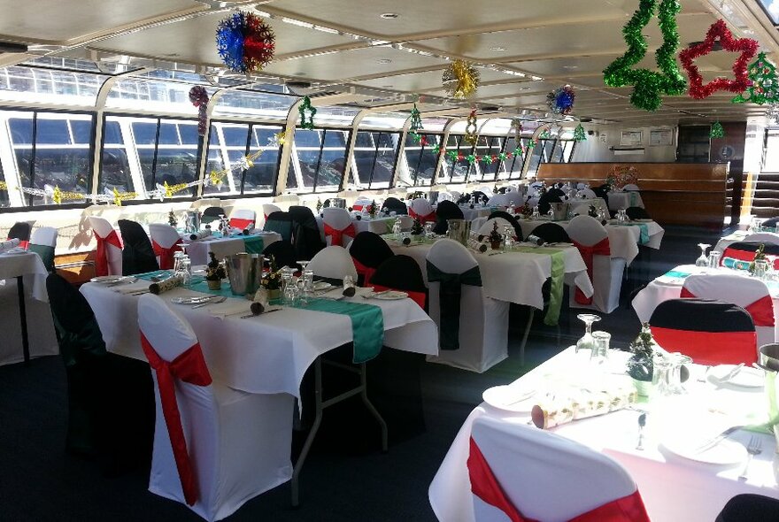 Tables decorated with Christmas ribbons and bonbons inside a cruise boat cabin.