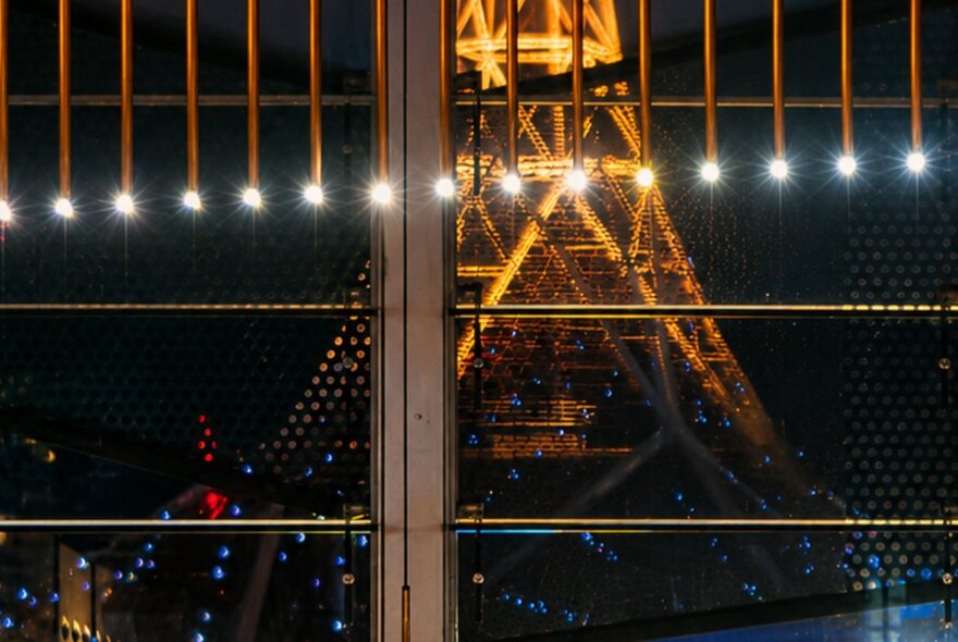 View through a window of the Arts Centre spire illuminated at night.