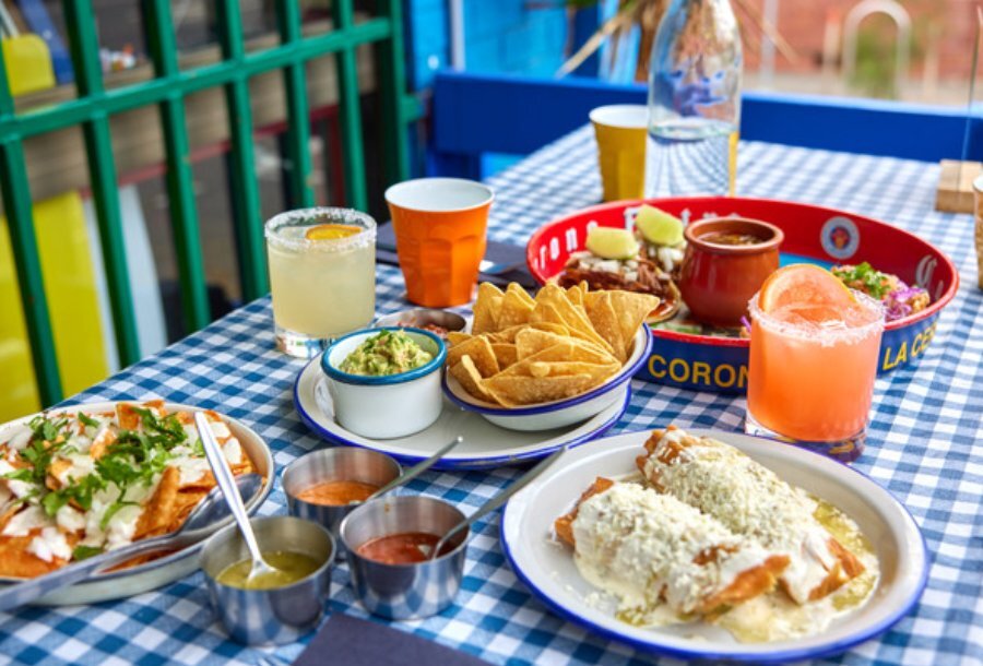 Table with corn chips, guac, nachos, and cocktails.