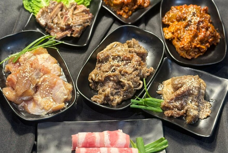 Looking down on a table full of an assortment of Korean dishes. 