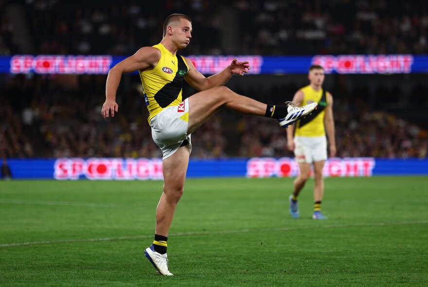 Richmond  AFL football players on the field during a match, one of them kicking a ball.