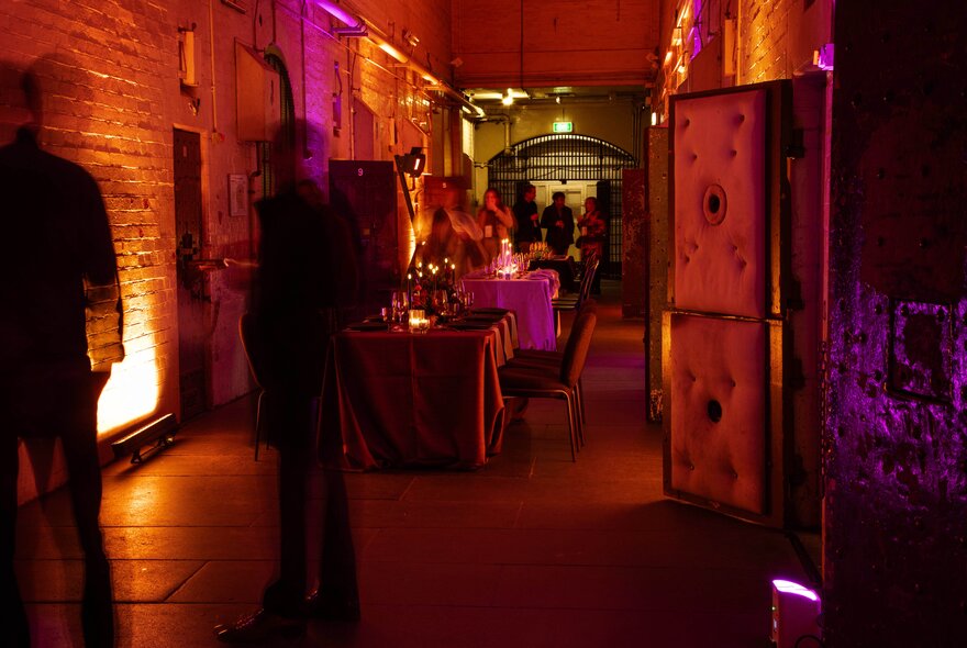 The Old Melbourne Gaol dungeon at night with orange and pink lighting.