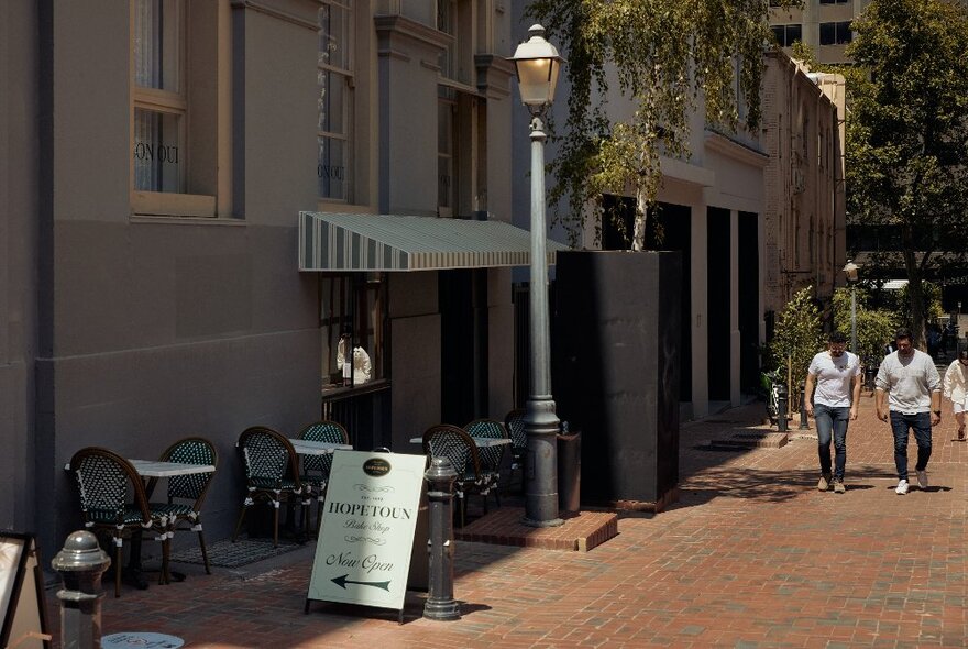 People walking along a Melbourne laneway with a sign pointing to the tearooms.