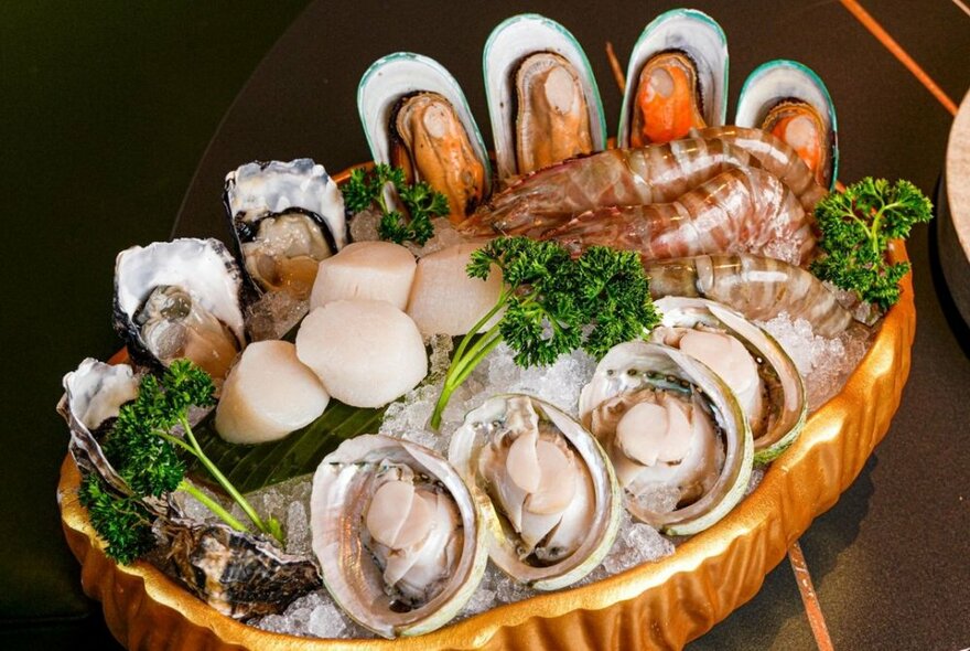 Seafood platter with mussels, scallops and prawns on ice with parsley.