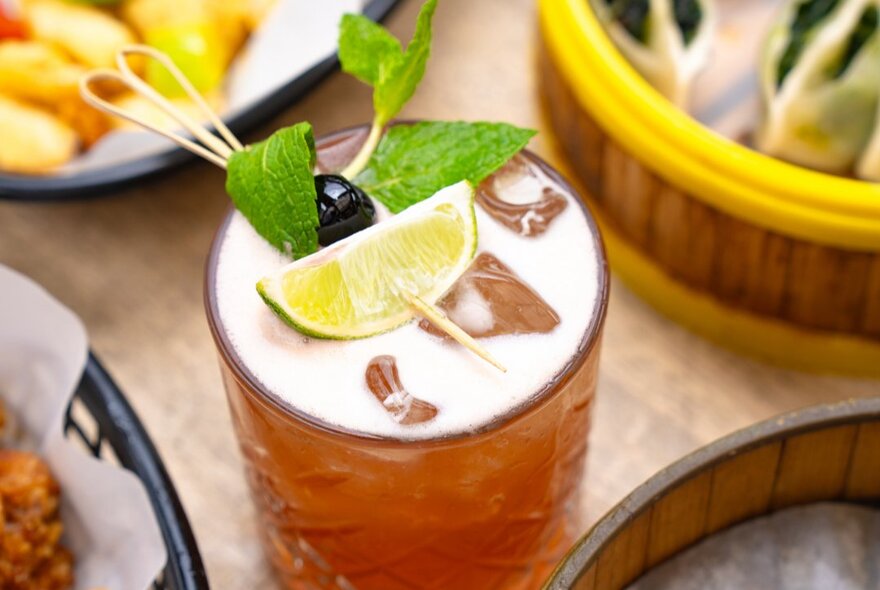 Close up of a cocktail with a lemon and mint leaf garnish.