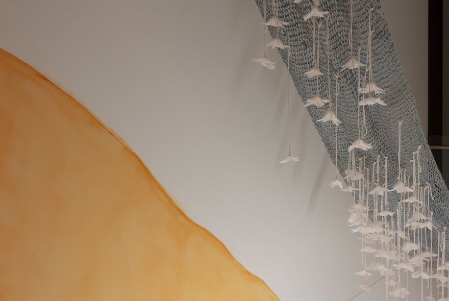 Installation in a gallery, with sculptures comprised of rope and netting hanging from the ceiling.