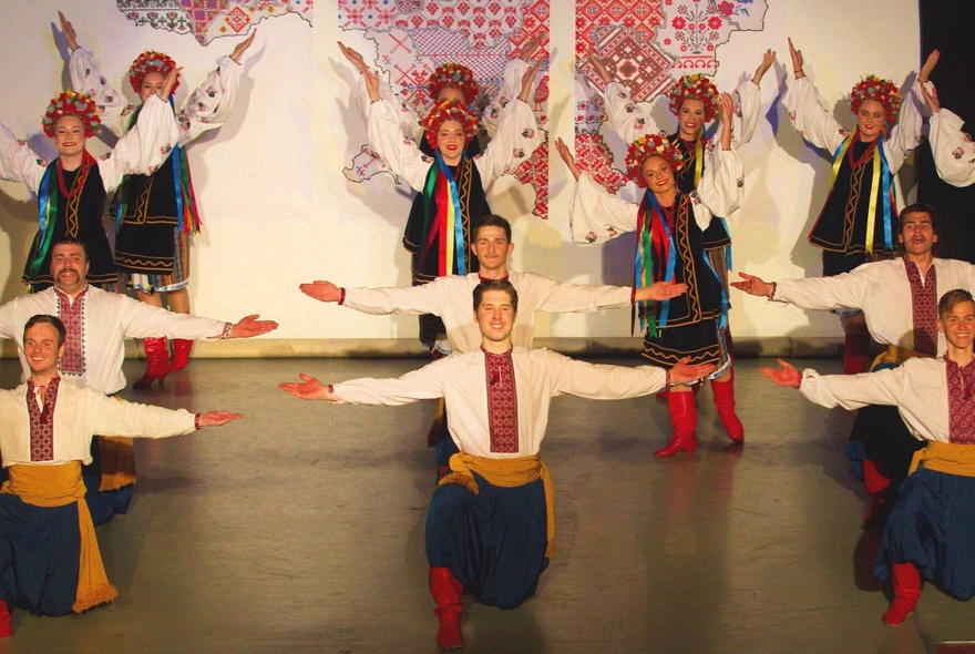 Traditional Ukrainian folk dancers in costume performing on a stage. 