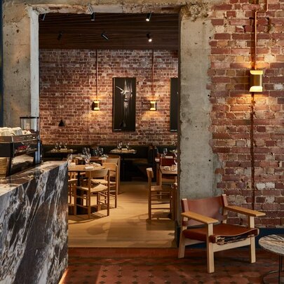 Restaurant interior with bare brick walls and wooden furniture.