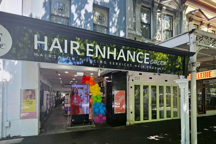 Store entrance on a leafy street with signage.