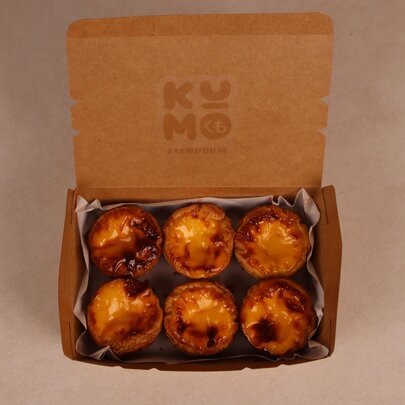 An open box containing six Portuguese tarts.