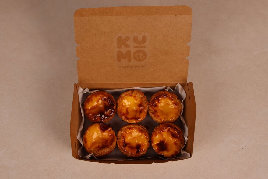 An open box containing six Portuguese tarts.