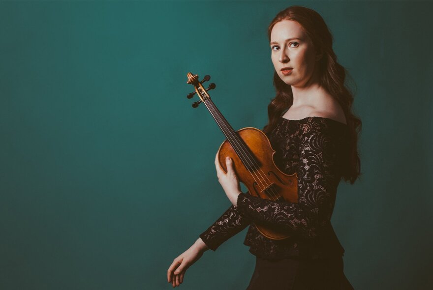 Violinist Augusta McKay Lodge holding her violin in her left hand. 