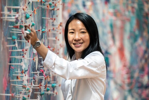 Pastry chef Janice Wong, smiling and standing next to a wall.