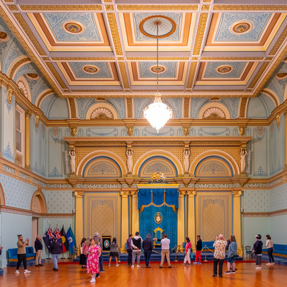 Crowds exploring an ornate government house room styled in blue and gold.