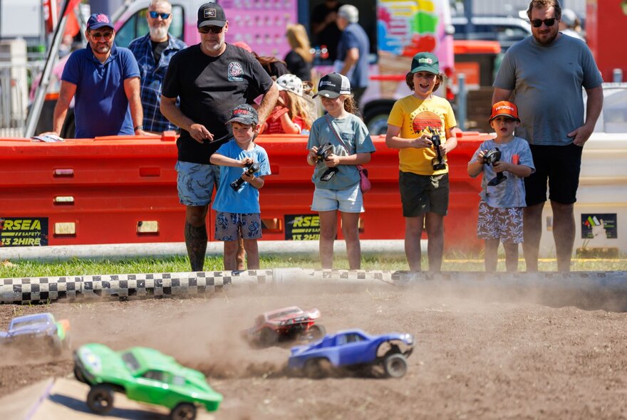 Young kids playing with remote controlled cars  in a dirt arena at a caravan and camping expo.