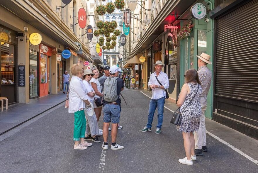Small tour group standing in a Melbourne laneway, listening to a man speaking.