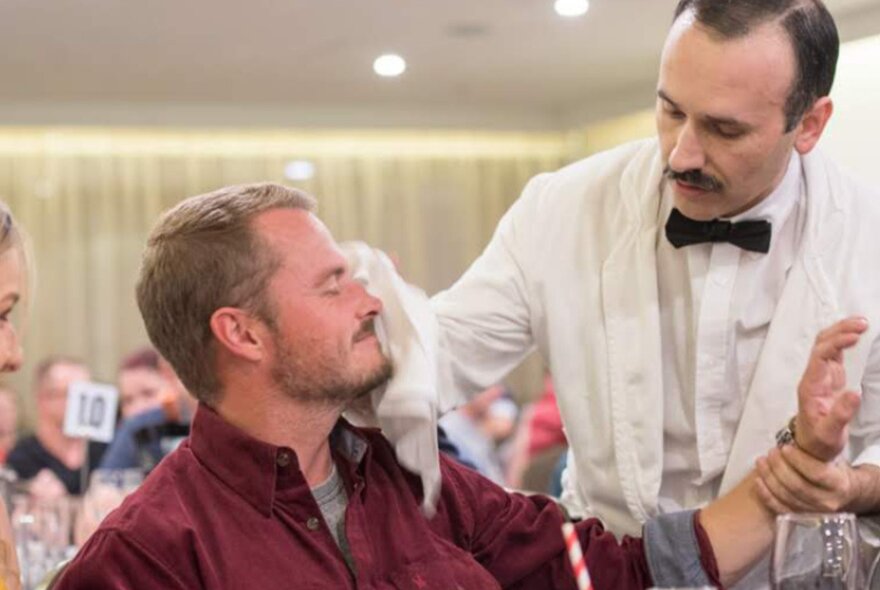 A man acting as Manuel from Fawlty Towers interacting with an audience member.