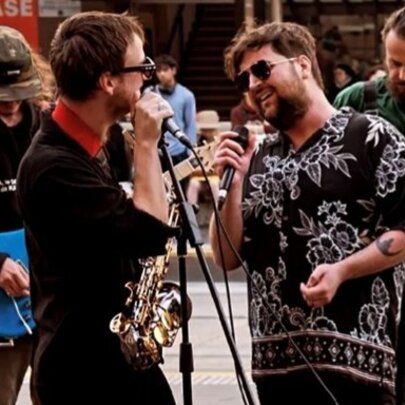 Two street performers singing into microphones, with two guitarists playing music behind them.