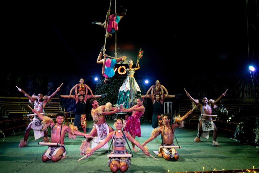 Performer on stage doing circus tricks, acrobats hanging in the air. 