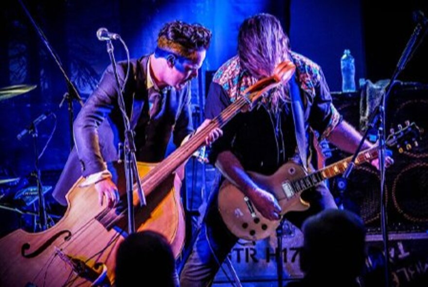 Two men on stage playing musical instruments in front of an audience.