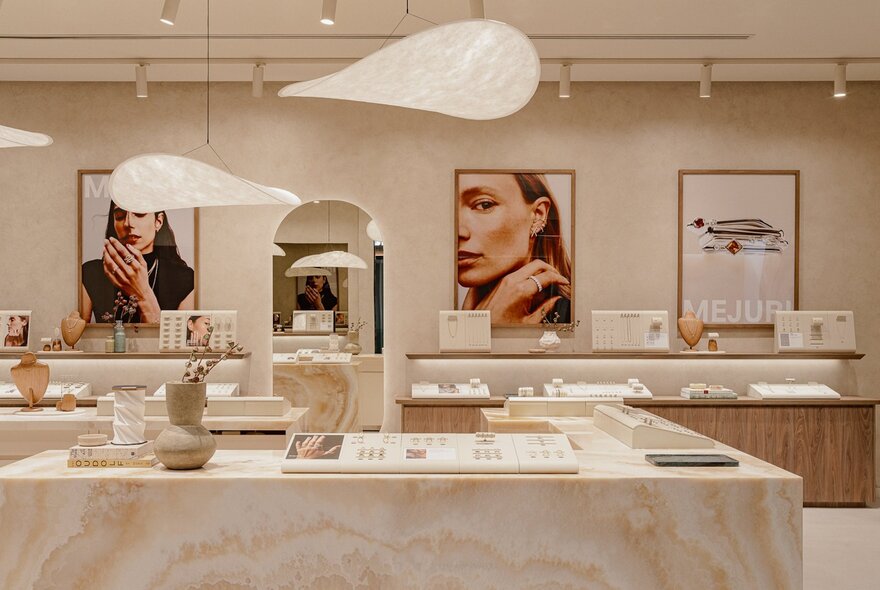 Interior of a high-end jewellery store with marble benches and large posters of models wearing jewels.