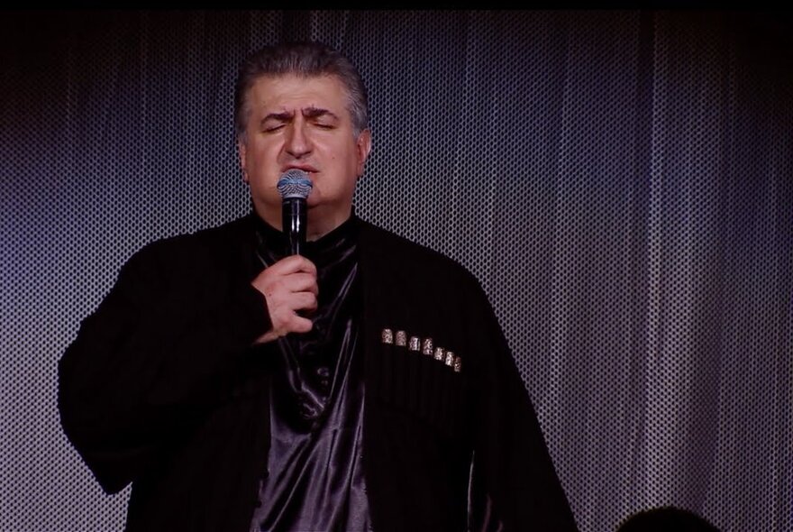 The Georgian singer and TV presenter Gia Bagashvili singing into a microphone on a stage. 