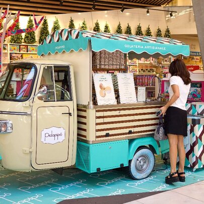 A woman ordering from a brown and blue ice cream truck inside a store.