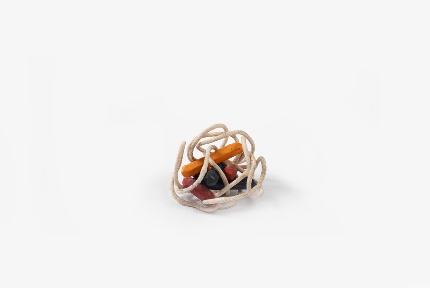 An balled up collection of white cord, around small orange coloured capsules, against a white background.