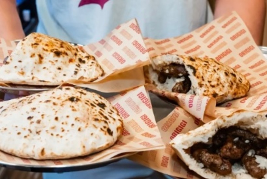 Pita style bread filled with cevapi and yoghurt, served on four plates. 