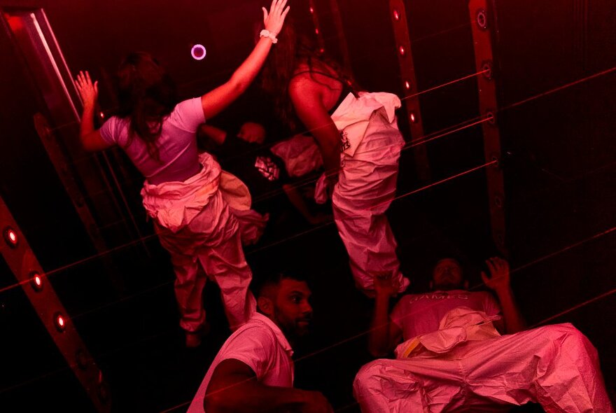 A team of four players wearing white boiler suits participating in an escape room style challenge in a confined space.