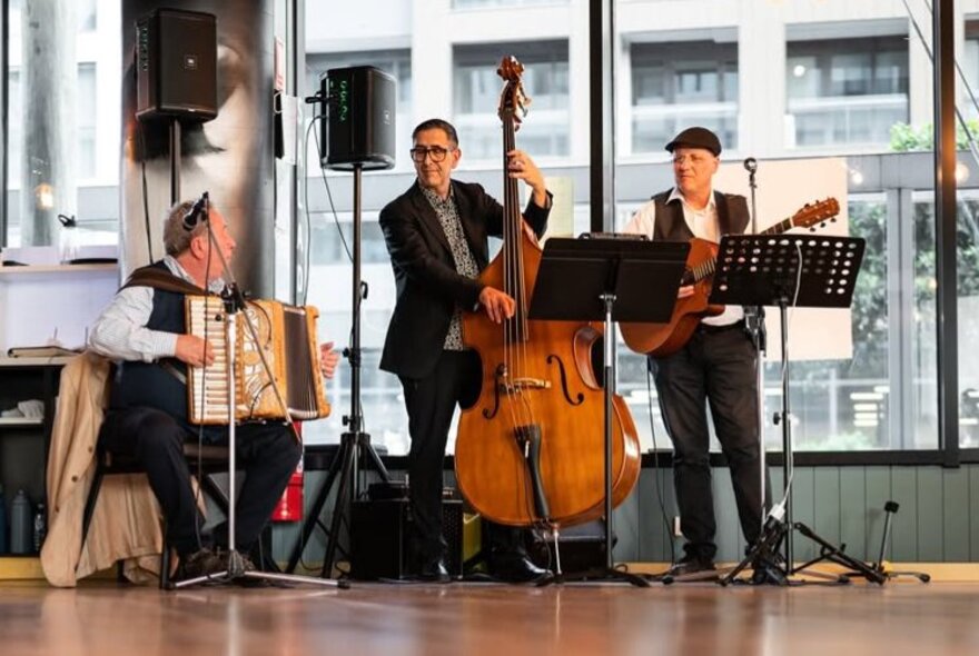 A three-piece band featuring an accordian, double bass and acoustic guitar.