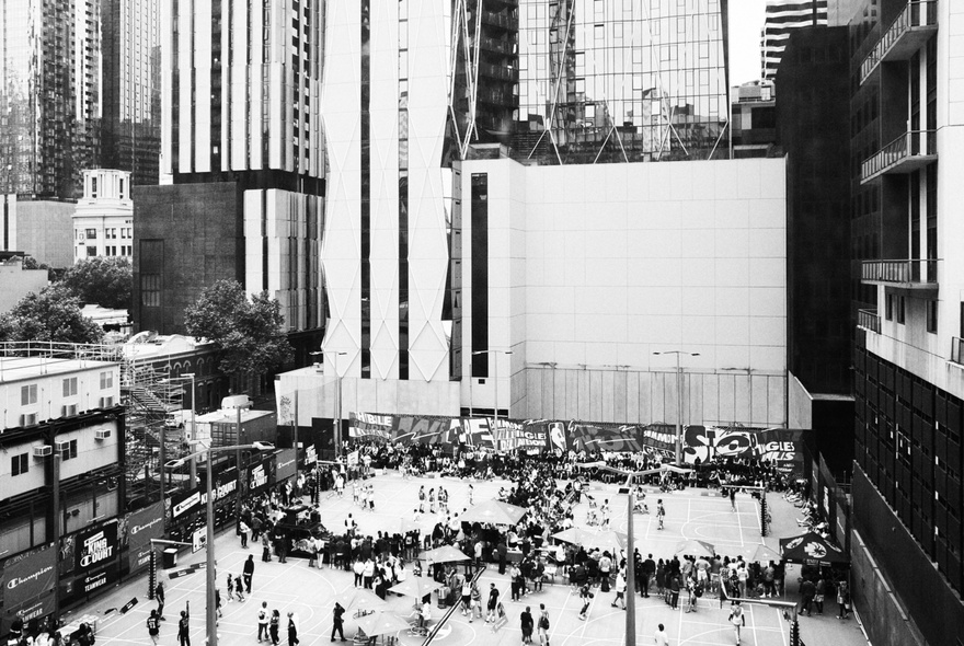 Crowds gathered around basketball courts dwarfed by surrounding city buildings.