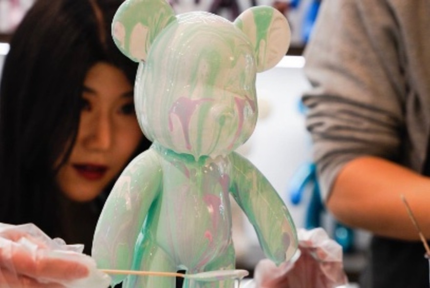 People adding paint to a bear statue.