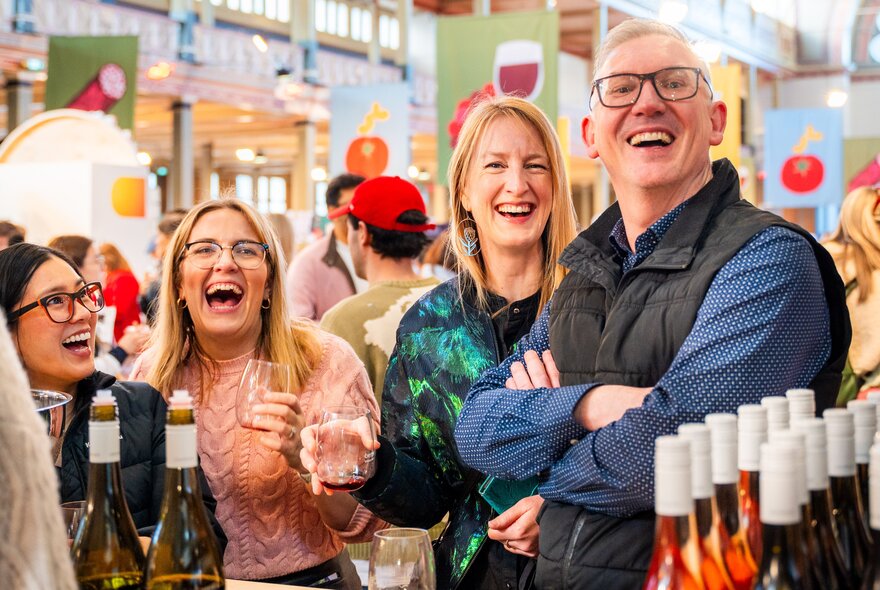 Smiling people next to bottles of wine at a food festival event.