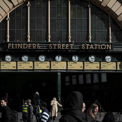 The steps of Flinders Street Station showing the row of clocks and people milling about underneath. 