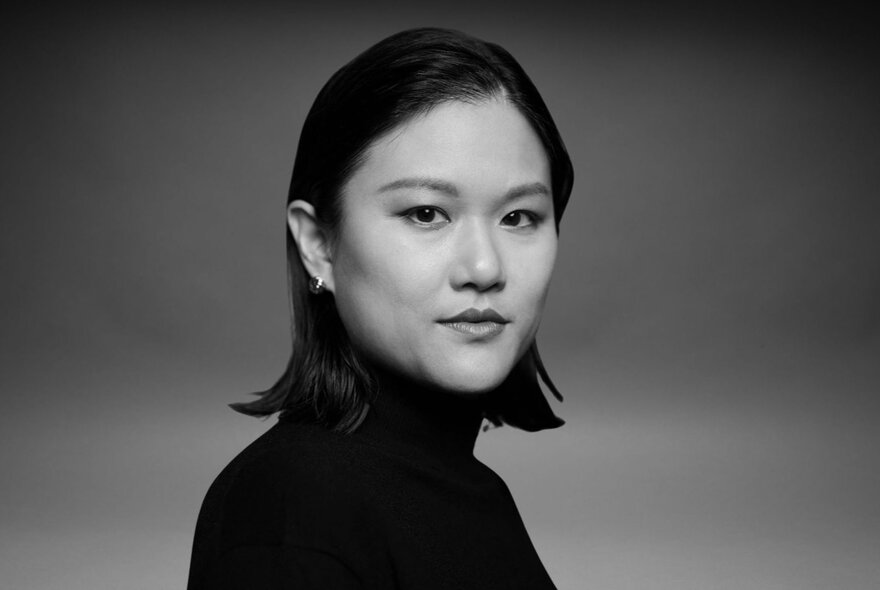 Author Karen Hao wearing black, against dark background.