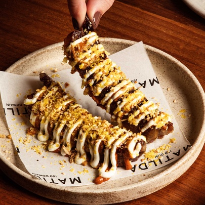 A plate showing two portions of smoked saltbush lamb ribs garnished with tahini yoghurt. 